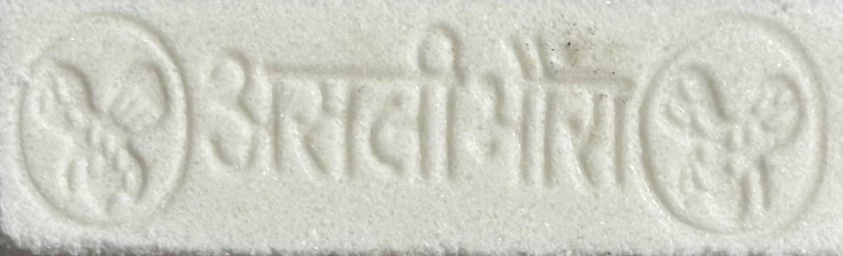 A bar embossed Asli Bhavra in Hindi with emblems at both ends